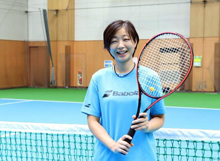 テニスラケットを持つ笑顔の安達コーチ
